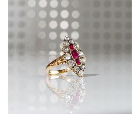 A gold, ruby and diamond set marquise shaped cluster ring, mounted with three cushion shaped rubies to the centre, in a surro