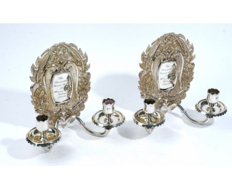 A pair of silver twin light candle wall sconces, the back plates of shaped oval form, decorated with tortoises, feathers and 
