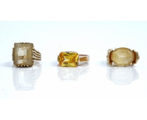 A 9ct gold ring, claw set with an oval cut citrine, a 9ct gold ring, claw set with a rectangular step cut citrine and a yello