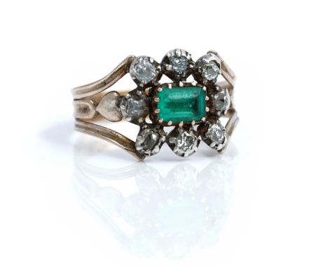 An early 19th century gold and silver set emerald and diamond cluster ring, mounted with the step cut emerald at the centre, 