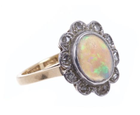 Opal and diamond cluster ring with an oval opal cabochon surrounded by a border of rose cut diamonds in platinum setting, on 