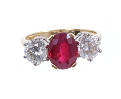 Ruby and diamond three stone ring with a central oval mixed cut ruby measuring approximately 8.80mm x 6.90mm x 4.15mm, flanke