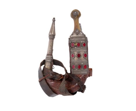 Late 19th century Arab jambia dagger with scabbard and horn grips, white metal and red glass mounts, carved blade with centra