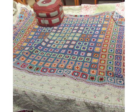 A large quilted bed spread together with a knitted bed spread and a pouffe