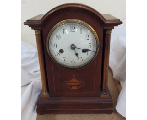 An Edwardian mahogany mantle clock, the domed top above a pair of ionic columns and a plinth base, the circular dial with Ara