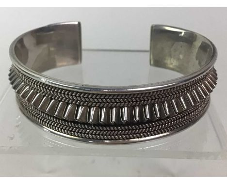 CONTINENTAL SILVER BANGLE, with cast borders of small curblinks flanked a folded border