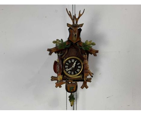 CUCKOO CLOCK, the circular black dial set with white Roman numerals, 