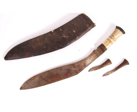 A mid 20th century Kukri knife having a shaped bone handle with ebonised wood and steel pommel. The curved blade having simpl