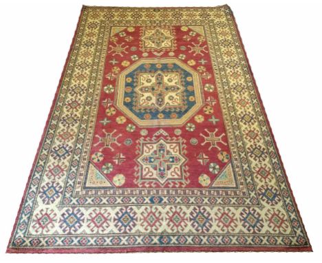 KAZAK CARPET, 270cm x 176cm, of multiple polychrome guls on ruby field.