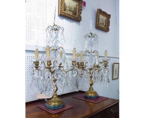 PAIR OF TABLE CHANDELIERS, with gilt metal and crystal columns, each with four lighting arms, allover hung with faceted glass