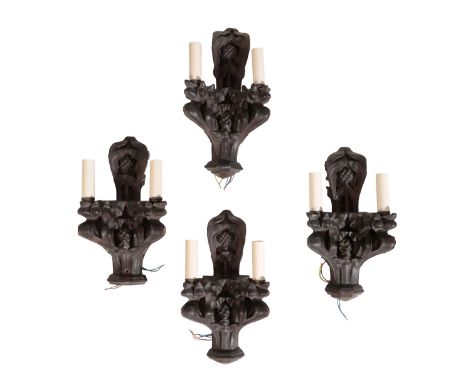 FOUR CARVED AND STAINED OAK TWIN LIGHT WALL APPLIQUES in Gothic style, early 20th century, the electrical sockets in stylised