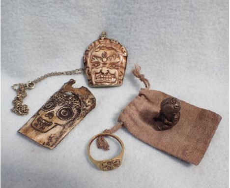 A BONE 'MEMENTO MORI' CARVING a pendant with grotesque face, an antique style brass ring, and a cast metal 'baby' with impres
