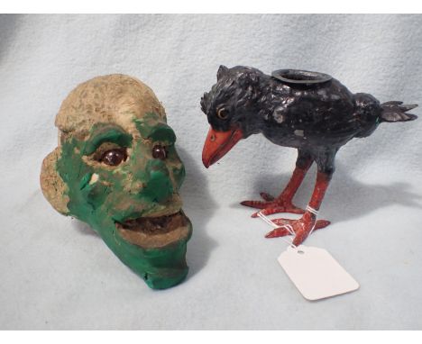 A SPELTER CANDLESTICK IN THE FORM OF A GROTESQUE BIRD and a papier mache ghoulish head (2)