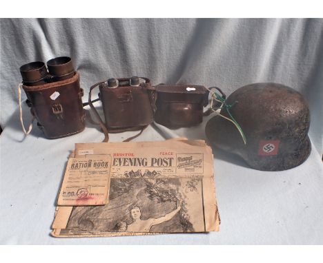 A GERMAN HELMET two pairs of binoculars, a camera , 1945 Peace edition newspapers, and a ration book