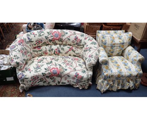 AN UPHOLSTERED KIDNEY SHAPED SOFA in all over floral print, 78cm high x 160cm wide x 85cm deep, and an upholstered armchair (
