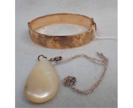 A ROLLED GOLD HINGED BANGLE AND A MOTHER OF PEARL PENDANT 