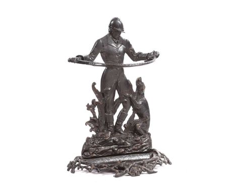 CAST IRON STICK STAND.HUNTSMAN AND WHIP. RAISED ON A PIERCED BASE. HEIGHT: 28 INCHES. WIDTH: 19 INCHES.DEPTH: 9 INCHES. IN GO