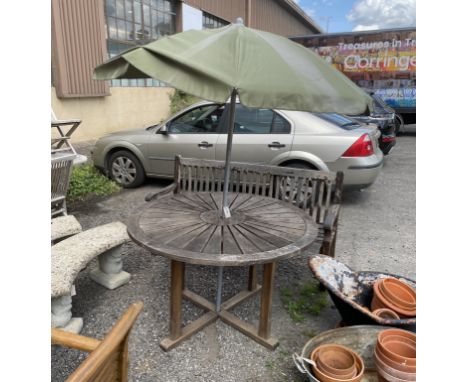 A circular weathered teak garden table, diameter 122cm, height 75cm parasol and bench