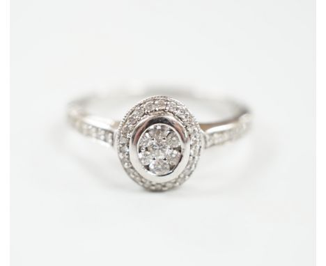 A modern 18ct white gold and diamond chip set oval cluster ring, size M/N, gross weight 3.2 grams.