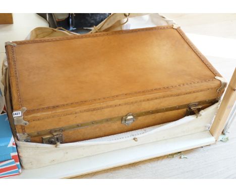 An early 20th century leather trunk, 90cm, in canvas outer wrapper