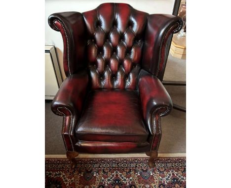 A single leather button back Chesterfield burgundy winged back armchair with metal braid detail on arms and wings with cabrio