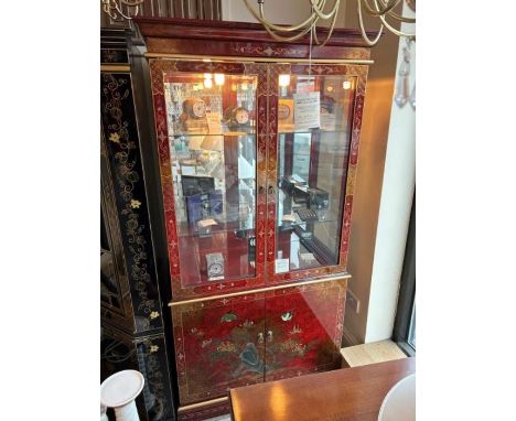 A red and gold lacquer double door display cabinet with bird detail to bottom section, the upper half having a mirror back an