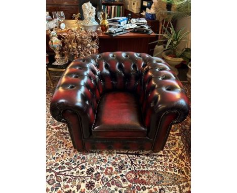 A single leather button back Chesterfield burgundy armchair with metal braid detail on arms and bun feet, manufactured by Man