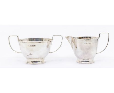 An Arts &amp; Crafts style silver milk jug and sugar bowl, hammered design and stylised handle, hallmarked by SSA, Birmingham