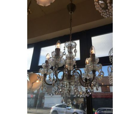 A five light chrome and Czech crystal chandelier, this heavily dressed chandelier has double glass sconces on each arm and on