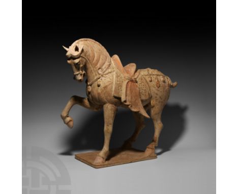 Tang Dynasty, 618-907 A.D. A ceramic horse modelled in the round prancing on a rectangular base, right foreleg bent and raise