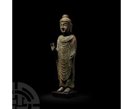 Northern Qi, 6th-7th century A.D. An Uddiyana style Buddha modelled in the round standing, wearing an ankle-length robe with 