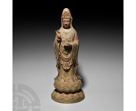 Wei Dynasty, 534-550 A.D. A ceramic figure of a standing Guanyin female modelled in the round on a waisted lotus-flower base;