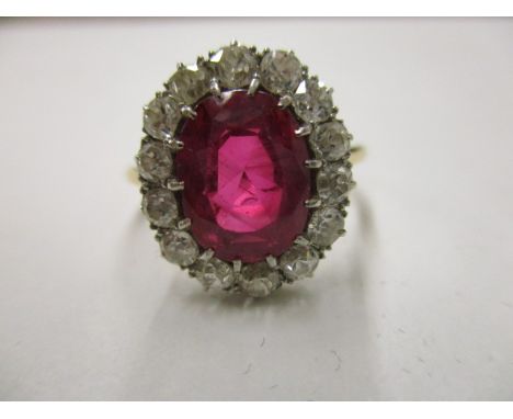 An 18ct gold ring set with fourteen diamonds around a ruby which is approximately 9mm x 7mm 