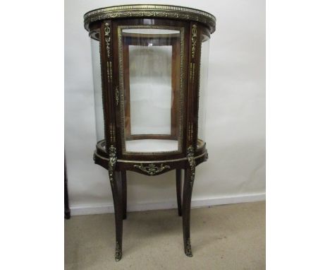 An early 20th century Louis XV style  mahogany oval display cabinet with brass mounts having a glazed top with a gallery over