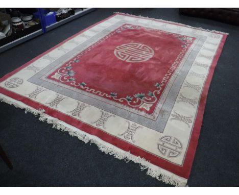 A large fringed embossed Chinese carpet on pink ground 