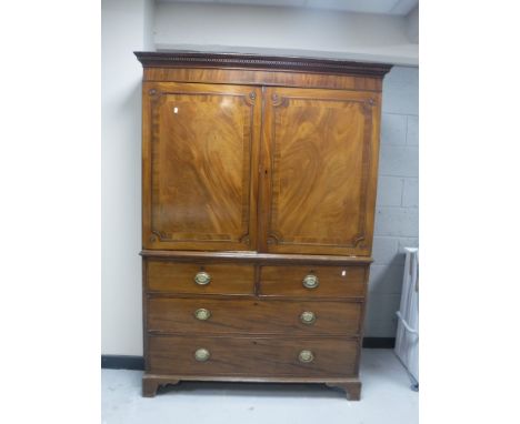 A George III inlaid mahogany linen press, with dentil moulded cornice, fitted four drawers with brass drop-handles cast with 
