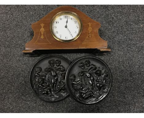 A French inlaid mahogany eight day mantel clock and a pair of carved ebonised wall plaques of cherubs 