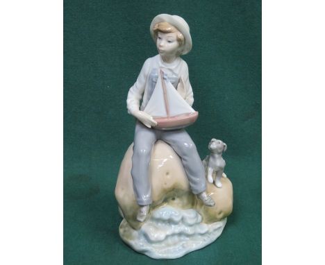 LLADRO GLAZED CERAMIC FIGURE OF A BOY WITH DOG AND MODEL YACHT, APPROXIMATELY 24cm HIGH