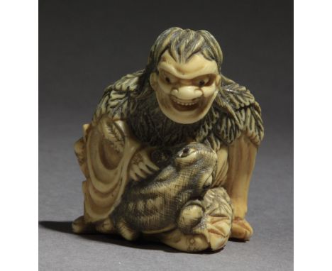 In carved elephant tusk portraying a Gama Sennin sat on the floor and grabbing a toad's leg, 39,6x33,3x21,6 mm. 18,33 gr. Wit