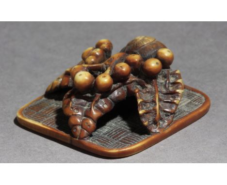 Not signed. In carved elephant tusk portraying a snail that is moving through a leaf with fruits, placed on a mat, 13,2x32,8x