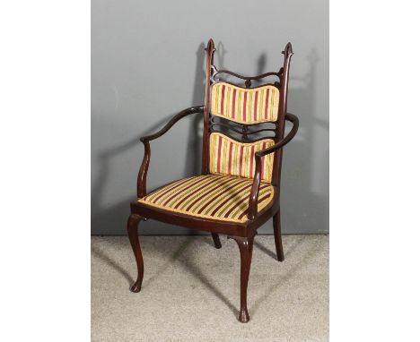 An Edwardian mahogany open arm chair of Art Nouveau design with pierced back and shaped arms, the back and seat upholstered i