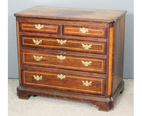 An oak chest of drawers of Georgian design inlaid with stringings and with mahogany crossbanding, with rounded front corners,