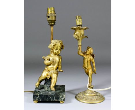 A gilt metal table lamp modelled as a seated putto holding a bunch of grapes, on green veined marble base with light fitting 