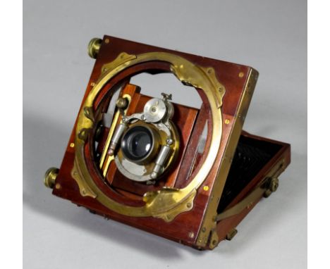 A late Victorian mahogany and lacquered brass folding plate camera by Bausch & Lomb, with three mahogany framed double sided 