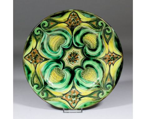 A Della Robbia pottery plate with a scraffito design of stylised pomegranates and leaves in tones of green and yellow, by Liz