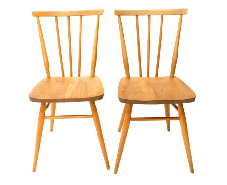 A pair of light coloured Ercol stick back kitchen chairs, each with an elm seat with turned back and legs. 