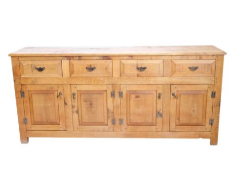 A light oak dresser, the plank top above four panelled drawers and four panelled doors, each with brass fittings, on stiles, 