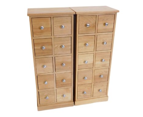 A pair of light oak chests, each with an arrangement of ten drawers, 105cm high, 42cm wide. 