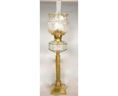 A brass table standing oil lamp, the reeded column on a stepped frame with moulded glass font, twin burner and etched shade