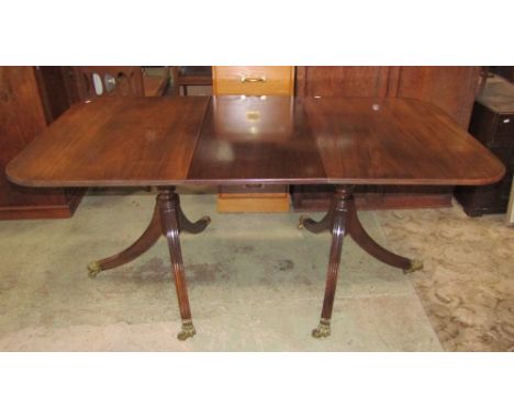 A reproduction Regency style twin pillar dining table with two additional leaves, reeded detail, swept supports with cast bra